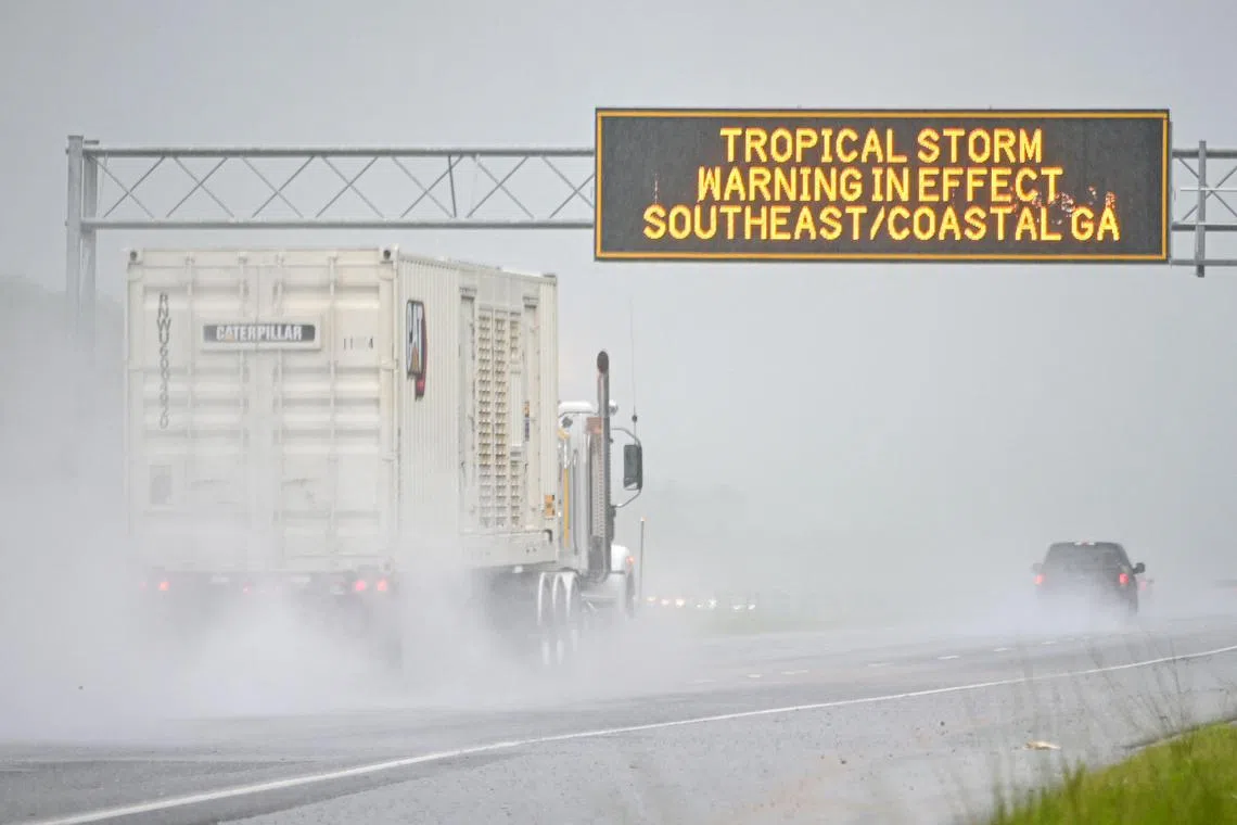 Vehicles drive through a flooded street caused by rain from tropical storm Debby in Savannah, Georgia. 