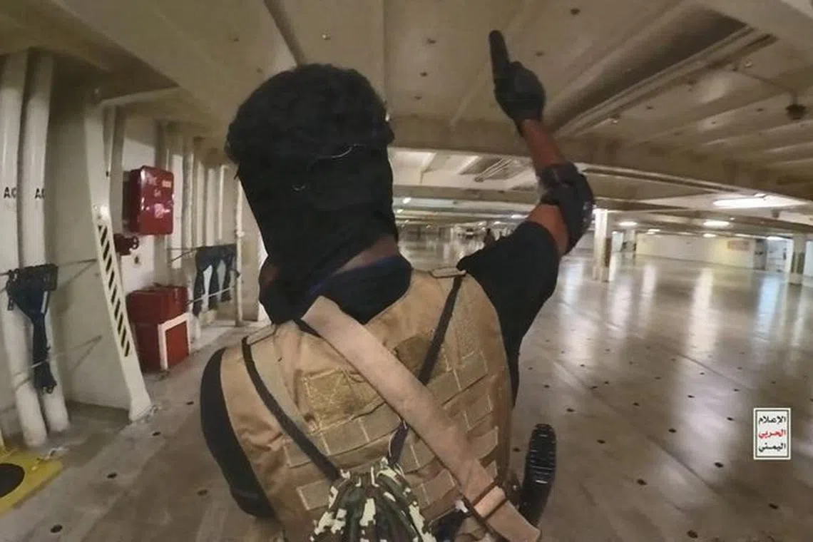 A Houthi fighter holds up a pistol in the cargo area of the Galaxy Leader cargo ship in the Red Sea in this photo released November 20, 2023. Houthi Military Media/Handout via REUTERS/File Photo
