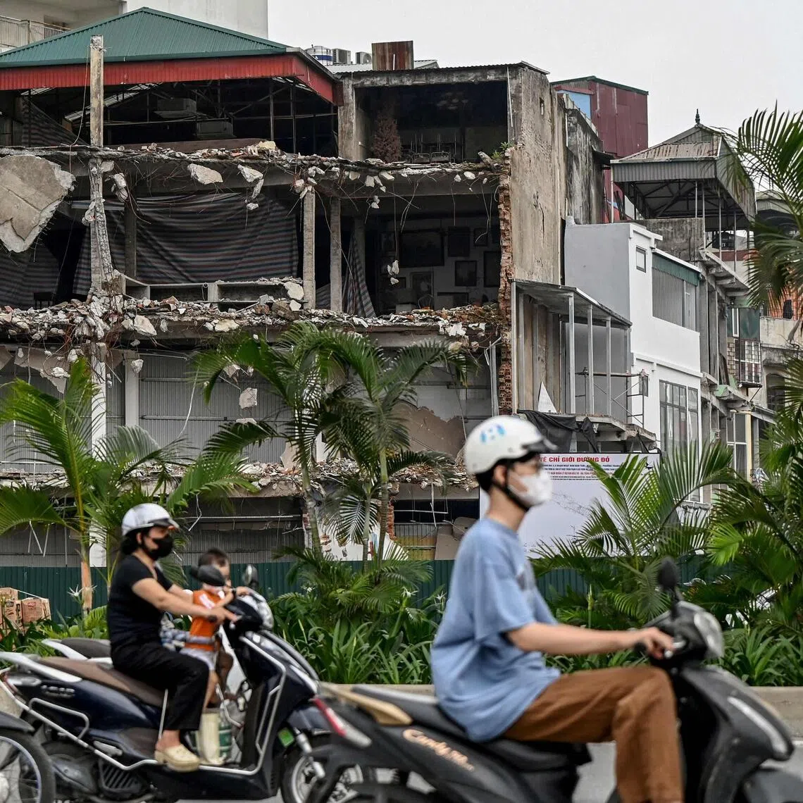 Motorcyclists commute past houses that have been demolished to widen a road in Hanoi on Aug 4.