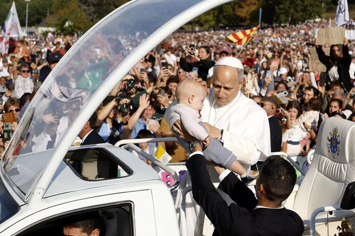 Pope Leo blessing a child as he arrives for mass at the Sanctuary of Our Lady of Lourdes in France on Sept 27.