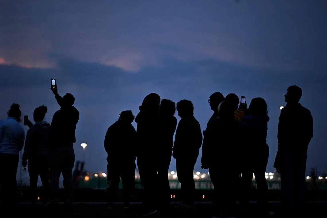 Onlookers looking at the Francis Scott Key Bridge that collapsed after being hit by the container ship Dali in Baltimore, Maryland, on March 26, 2024. 