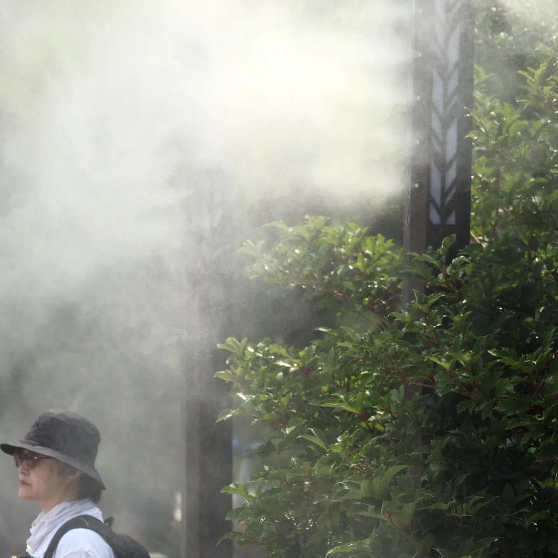 A person walks under a cooling fog system to escape the heat in Seoul.
