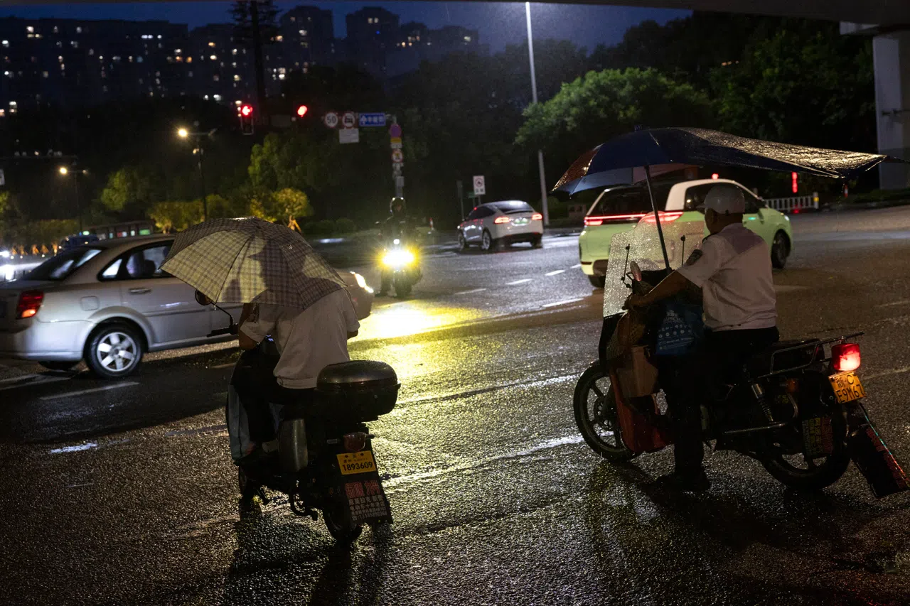 epa13104692 Commuters shelter under umbrellas while riding their motorbikes in the rain ahead of Typhoon Bavi's landfall, in Wenzhou, Zhejiang province, eastern China, 11 July 2026. China's National Meteorological Center (NMC) has issued several typhoon alerts ahead of Typhoon Bavi's expected landfall along the East China coastline between the evening of 11 July and early 12 July. Coastal areas in Zhejiang and Fujian provinces could see torrential rainfall of 250 to 400 millimeters. EPA/ANDRES MARTINEZ CASARES