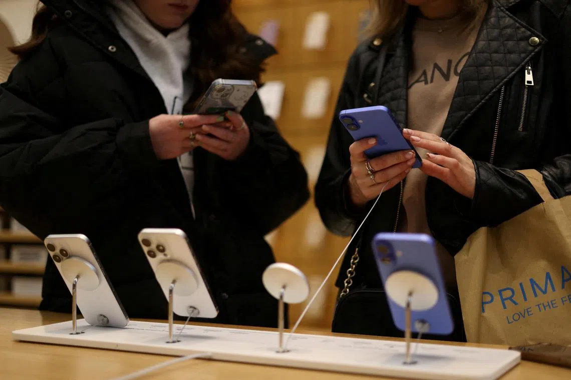 FILE PHOTO: People use Apple iPhone smartphones at a store in London, Britain, October 6, 2024. REUTERS/Hollie Adams/File Photo