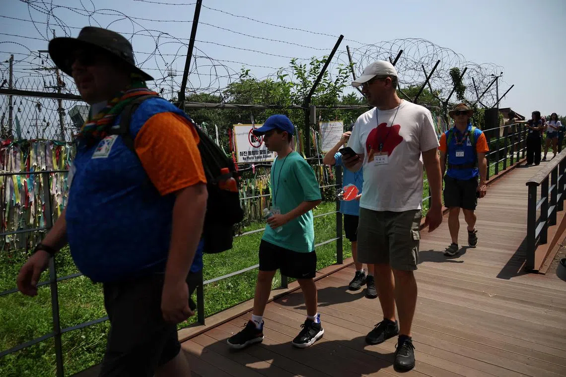 Foreign tourists participating in DMZ tour walk past a military fence near the demilitarized zone separating the two Koreas, in Paju, South Korea July 19, 2023.   REUTERS/Kim Hong-Ji
