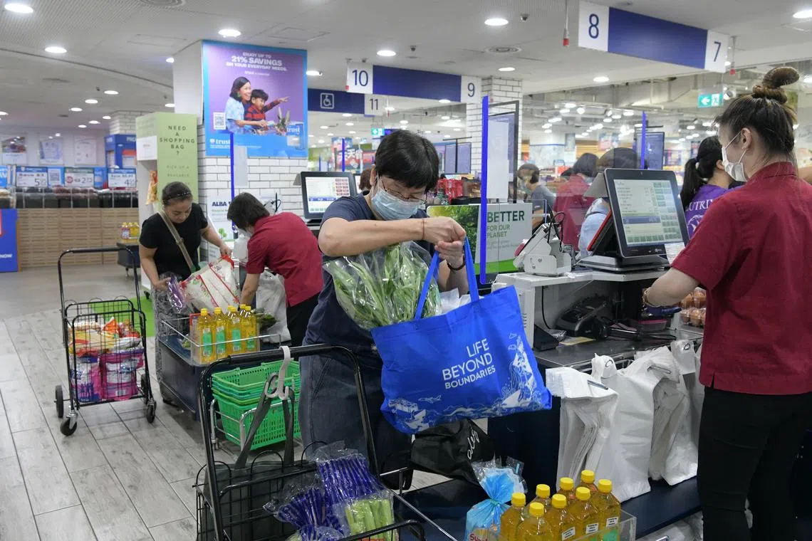 Shoppers at a FairPrice outlet using their own bags while buying groceries, on July 3, 2023.