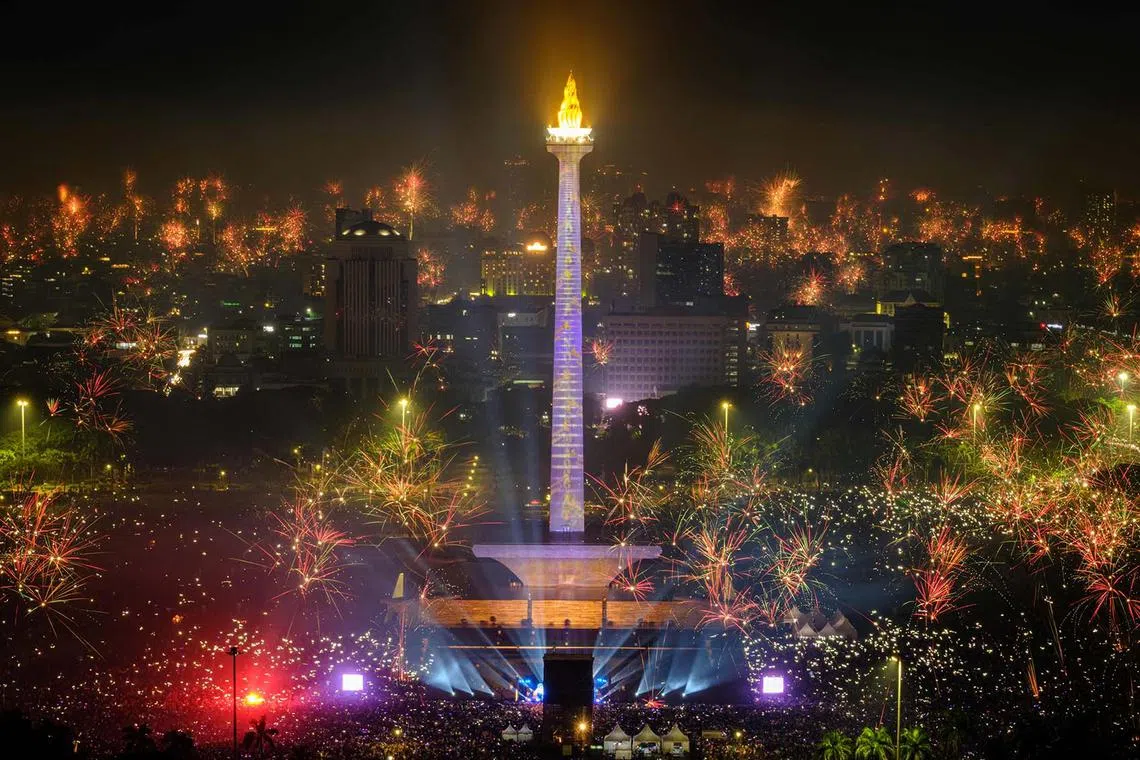 Fireworks exploding over the city to usher in the New Year, as revellers gather around as the lit National Monument of Indonesia (MONAS) in Jakarta on Jan 1, 2024. 