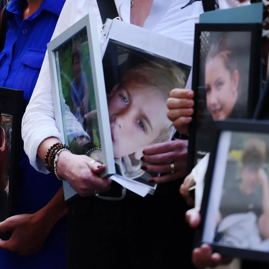 Bereaved parents in London hold portraits of their children who they say died as a result of social media business practices.
