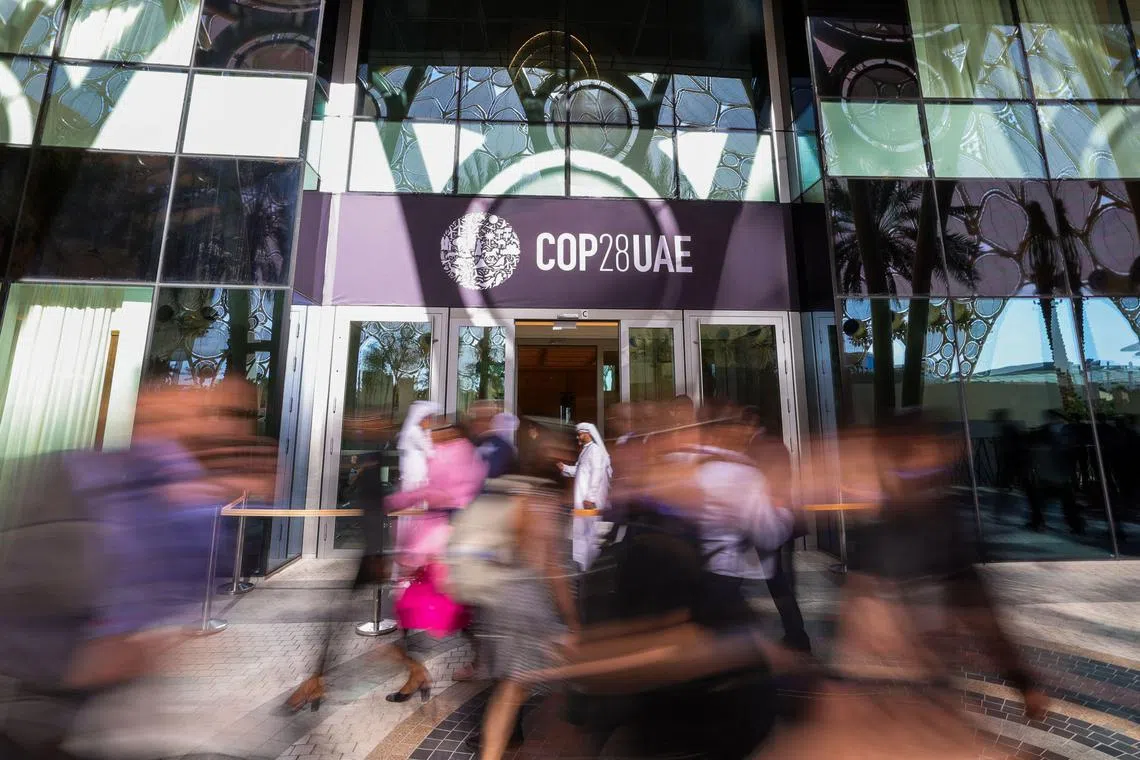 TOPSHOT - People arrive at the venue of the COP28 United Nations climate summit in Dubai on November 30, 2023. The UN climate conference opens in Dubai on November 30 with nations under pressure to increase the urgency of action on global warming and wean off fossil fuels, amid intense scrutiny of oil-rich hosts UAE. (Photo by Giuseppe CACACE / AFP)