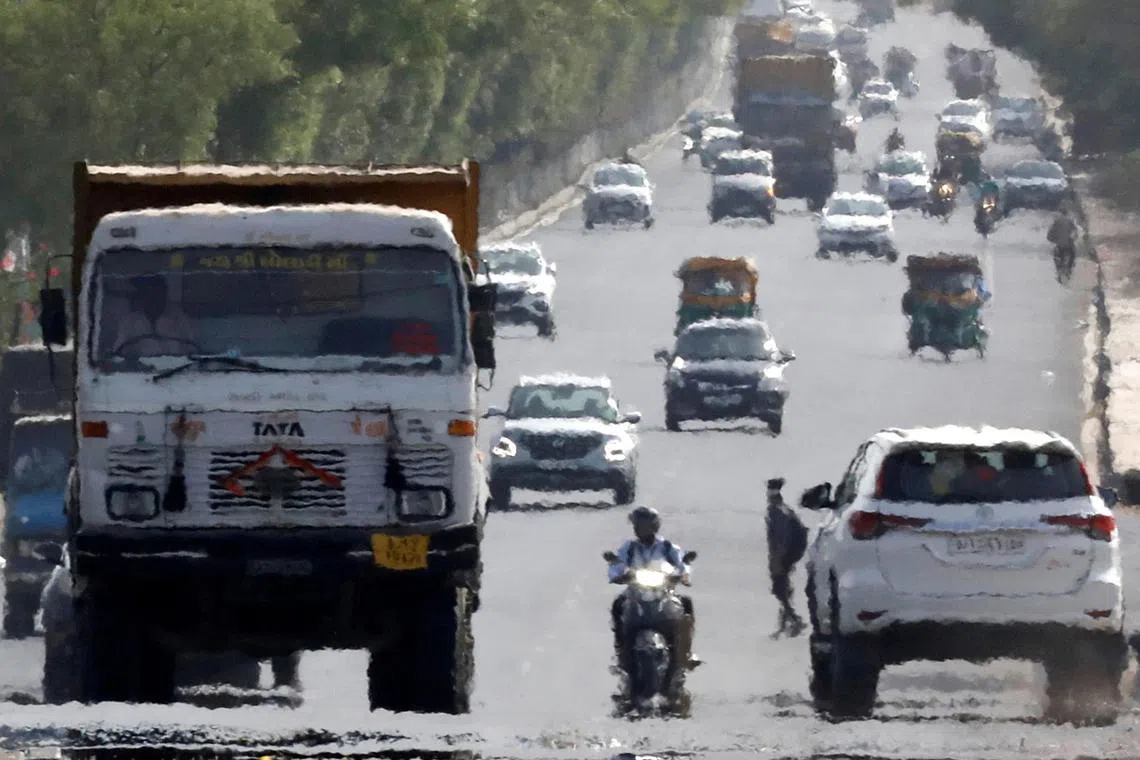 FILE PHOTO: Traffic moves on a road in a heat haze during hot weather on the outskirts of Ahmedabad, India, May 12, 2022. REUTERS/Amit Dave/File Photo
