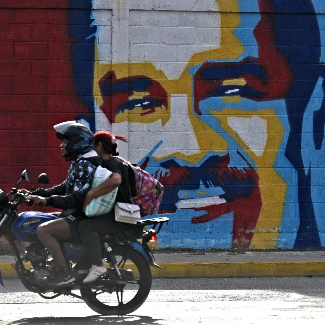A motorcyclist rides past graffiti depicting Venezuelan President Nicolas Maduro in Caracas on Jan 3.  US President Donald Trump announced US forces had captured Mr Maduro in a large-scale assault.
