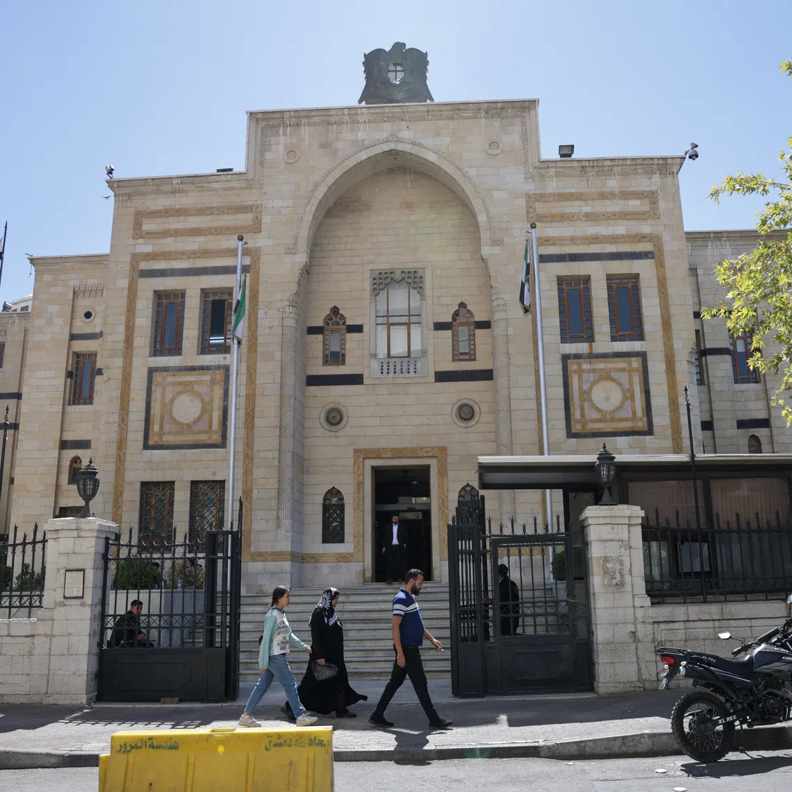A group of civilians walk past the main gate of the Syrian parliament building, in Damascus, Syria September 3, 2025. REUTERS/Khalil Ashawi