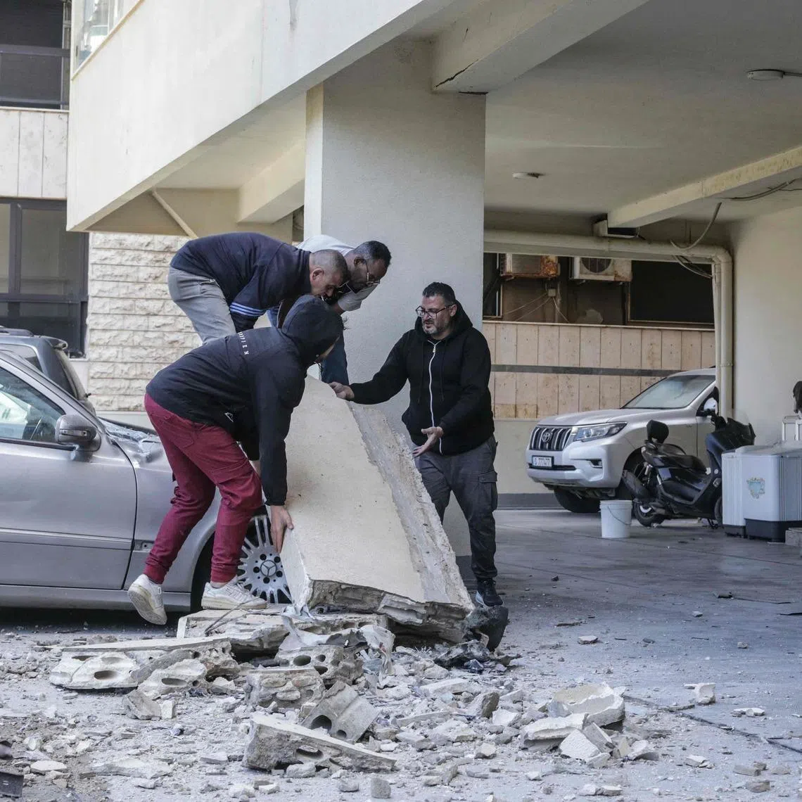 Residents trying to move a block of concrete from a car at the site of an Israeli strike in Beirut on March 28. Three journalists were reported killed in a strike in south Lebanon on the same day.