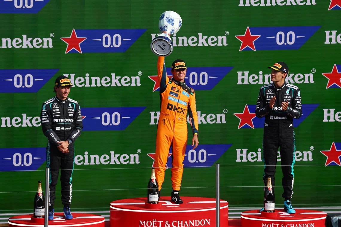 Formula One F1 - Dutch Grand Prix - Circuit Zandvoort, Zandvoort, Netherlands - August 23, 2026 McLaren's Lando Norris celebrates on the podium with the trophy after winning the Dutch Grand Prix alongside second placed Mercedes' Andrea Kimi Antonelli and third placed Mercedes' George Russell REUTERS/Jakub Porzycki