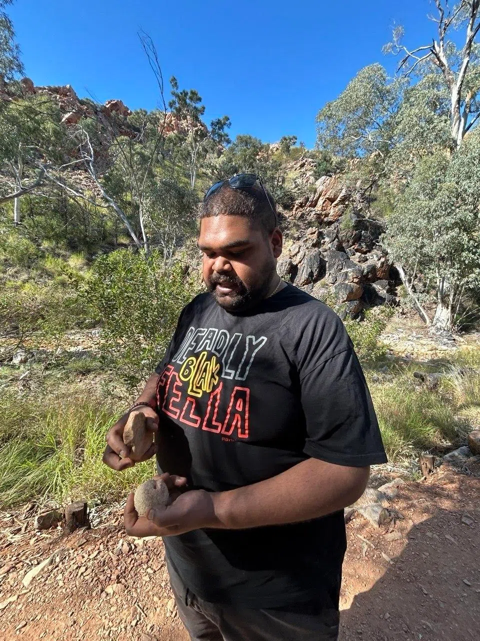 Tour guide Brodie Roesch showing visitors how to crack open a bush coconut.