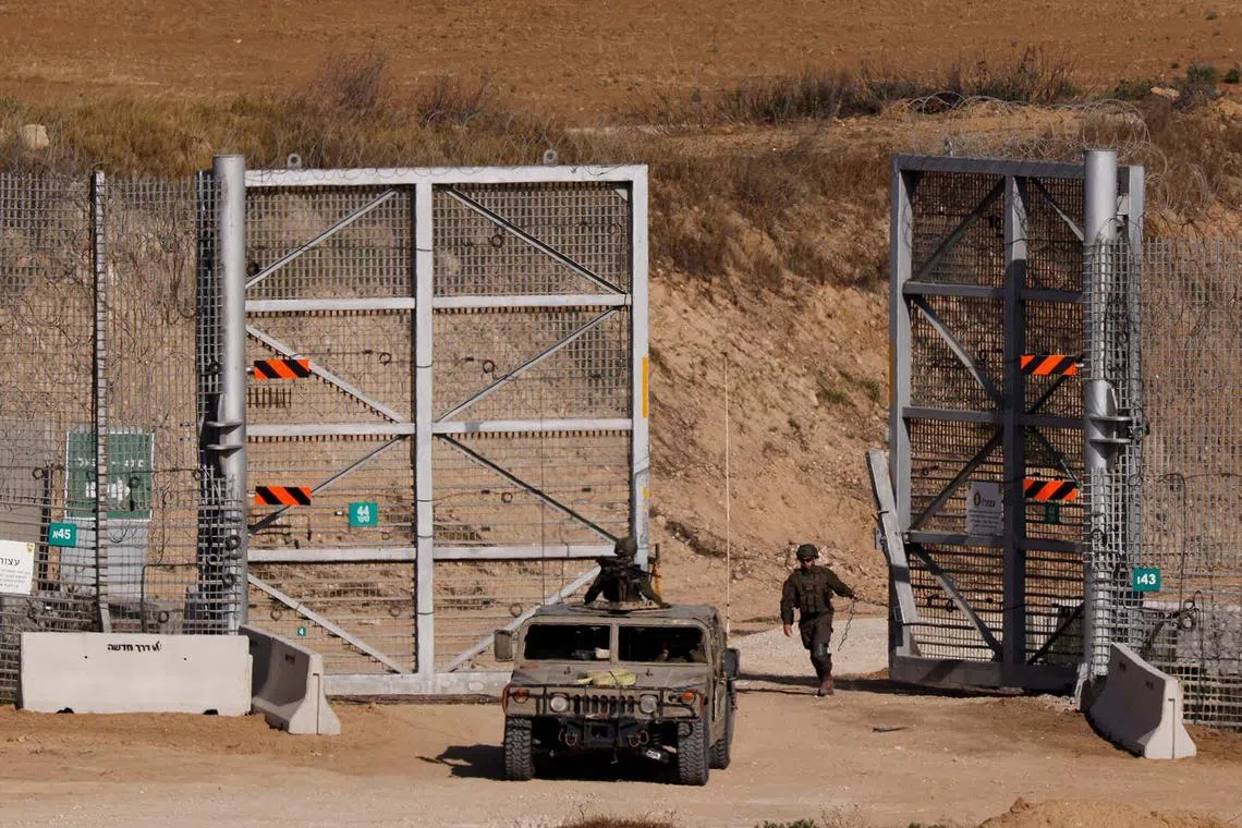 An Israeli soldier closing a gate at the border fence with Gaza, as seen from Israel, May 20, 2025. 
