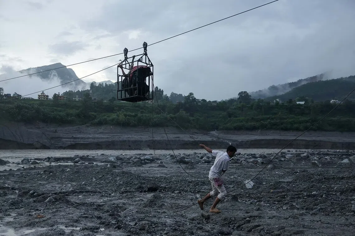 A man pulls a makeshift zip line carrying people across the Trishuli River from Koloni after landslides and mudslides damaged bridges, leaving people temporarily stranded in Trishuli, Nuwakot district, Nepal, September 2, 2026. REUTERS/Francis Mascarenhas TPX IMAGES OF THE DAY
