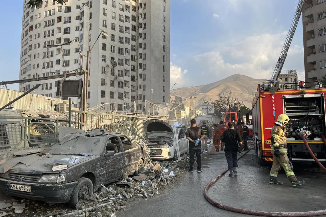 Firefighters work outside a building that was hit by Israeli air strikes north of Tehran.