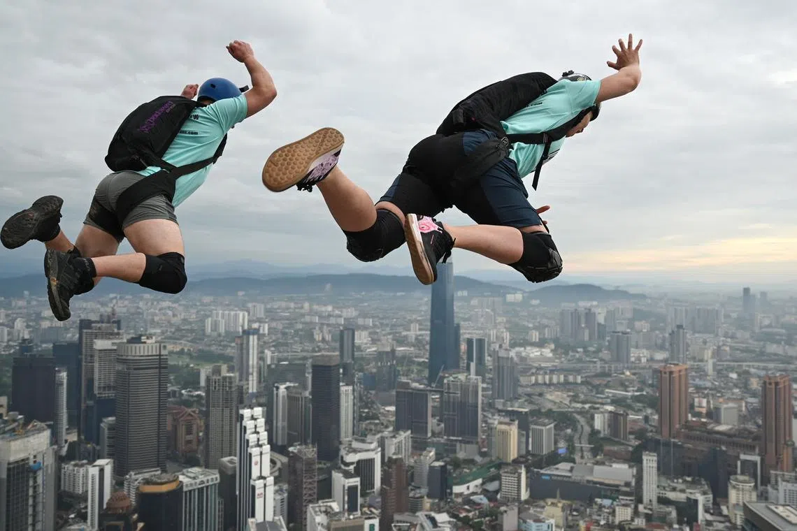 Base jumpers from Canada, Jeremy Bruns (L) and Kelsey Fry (R), leap from the 300-metre high open deck of Malaysia's landmark Kuala Lumpur Tower during the International Tower Jump in Kuala Lumpur on Feb 3, 2023.