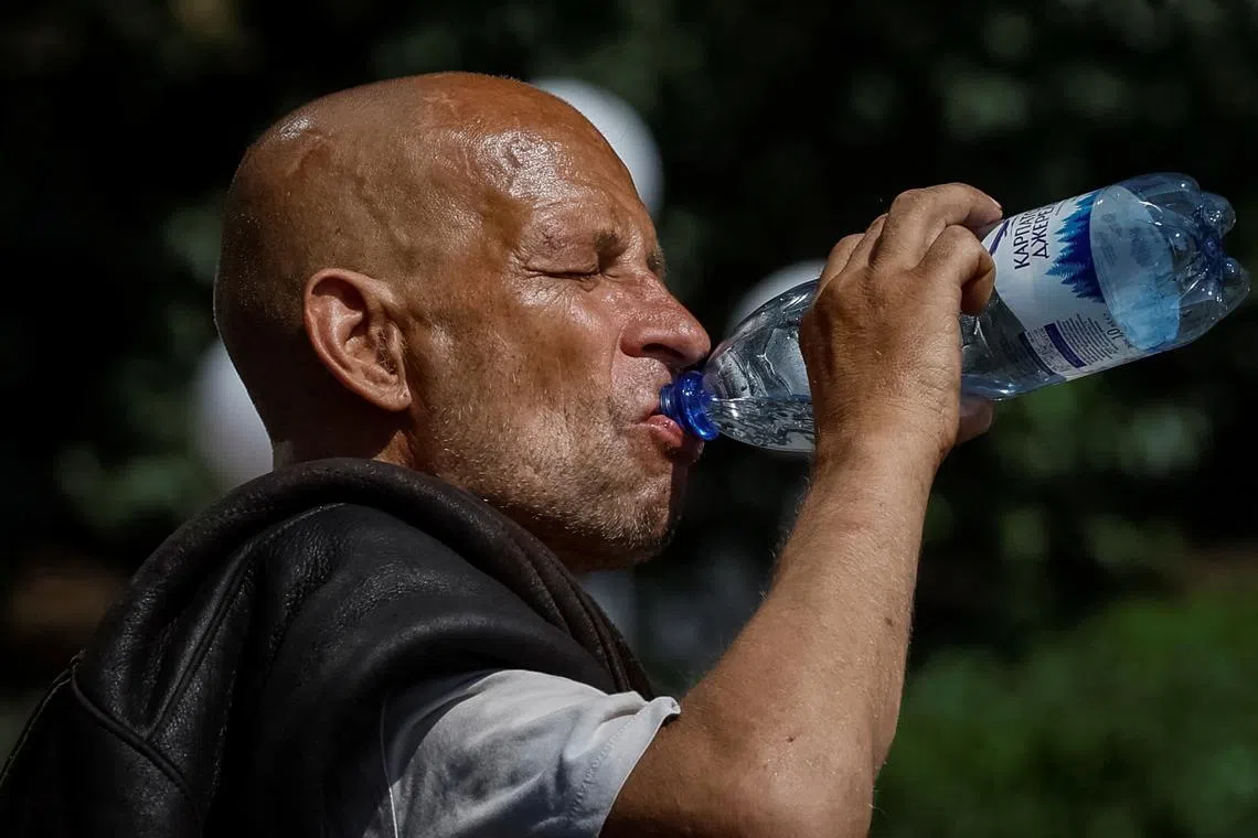 FILE PHOTO: A man drinks water on the street during an abnormally hot summer day, amid Russia's attack on Ukraine, in central Kyiv, Ukraine July 15, 2024. REUTERS/Gleb Garanich/File Photo