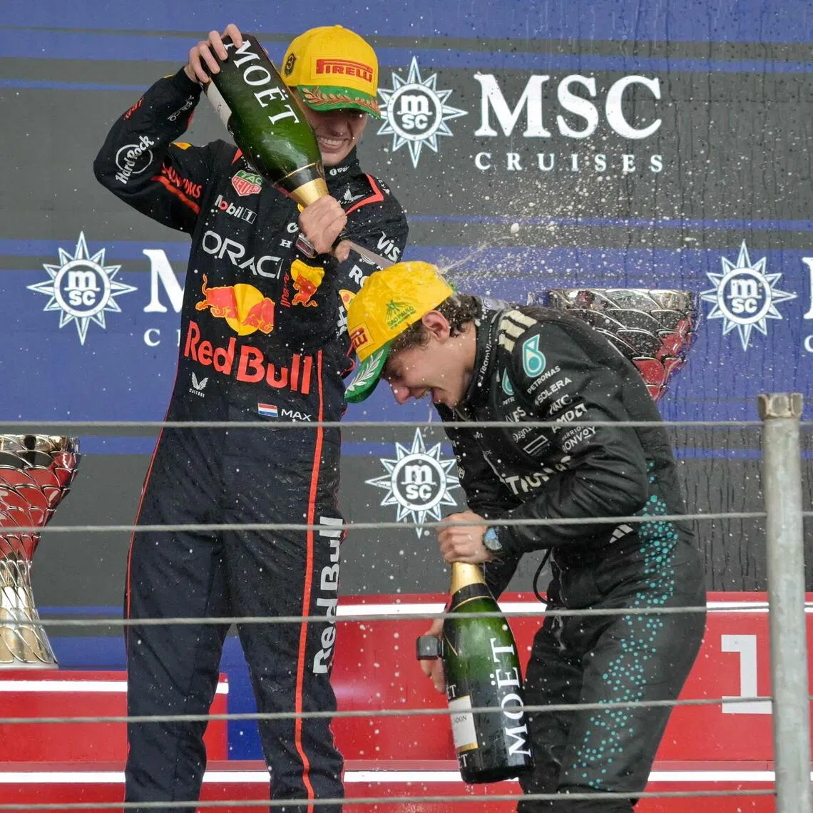Red Bull driver Max Verstappen (left) pouring champagne on Mercedes'Kimi Antonelli as they celebrate on the podium after the Sao Paulo Grand Prix.