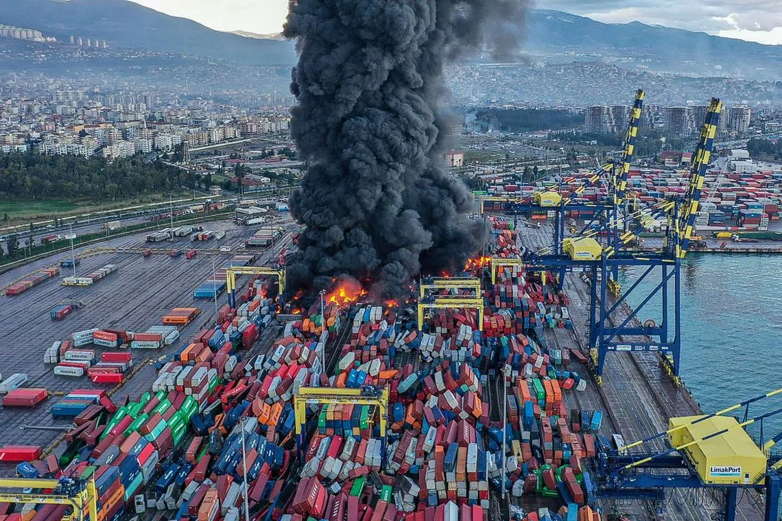 Handout photograph taken and released by Turkish agency DHA (Demiroren News Agency) shows smoke rising from burning containers at the harbour of Iskenderun in Hatay, a day after a 7.8-magnitude earthquake struck the country's southeast, on Feb 7, 2023. 