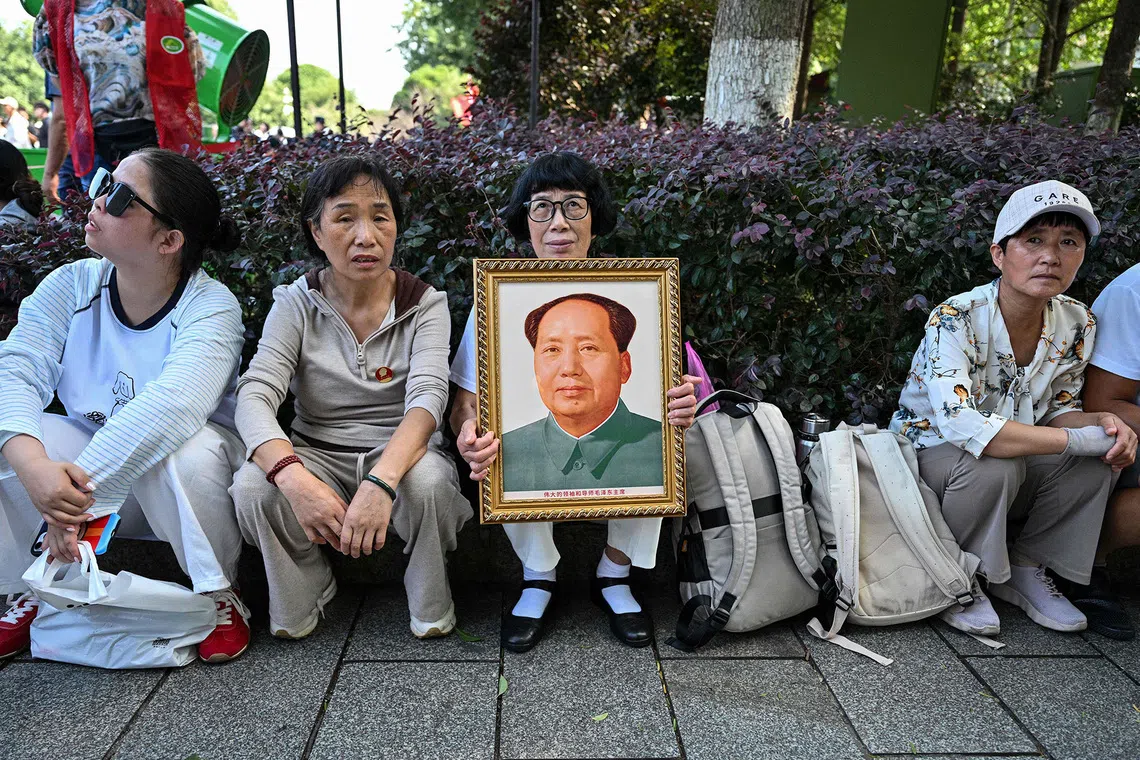 A woman holds a portrait of late Communist leader Mao Zedong while paying tribute at the Mao Zedong Bronze Statue Square in Shaoshan, China's central Hunan province on September 9, 2026, during the 50th anniversary of his death. (Photo by Hector RETAMAL / AFP)