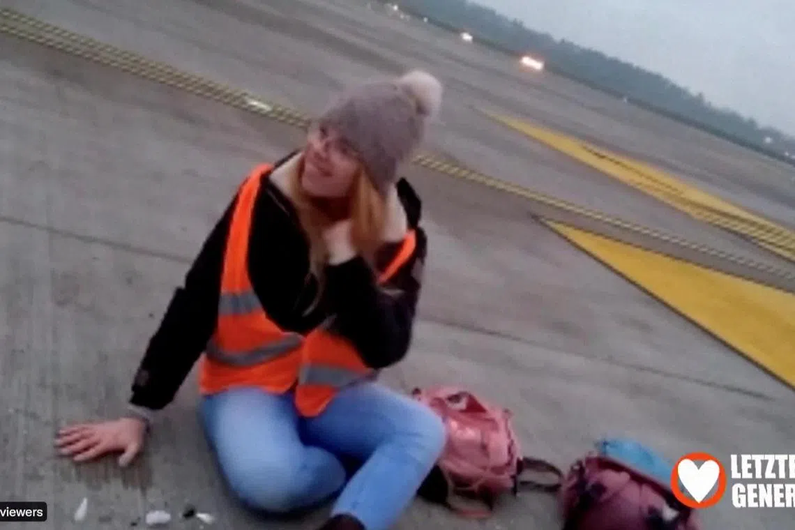 A climate activist glues herself to a runway at the Berlin Brandenburg Airport, on Nov 24, 2022.