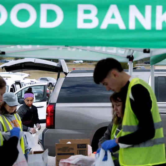 Volunteers place food items in vehicles during a mobile food distribution at Cedar Creek High School in Cedar Creek, Texas, on Nov 1.