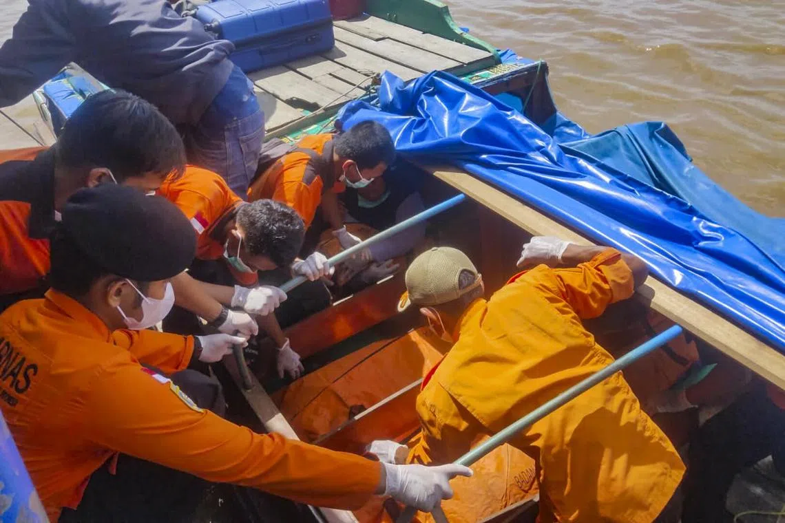 Rescuers with the body bags containing victims of the capsized speedboat in Indragiri Hilir Regency, Riau province, Indonesia, on April 28, 2023. 