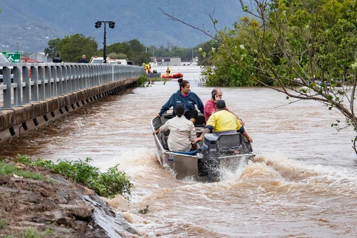 Residents cross floodwaters by boat in Cairns on December 18, 2023. Flash floods swamped northeastern Australia on December 18, with raging waters severing roads and flushing crocodiles into towns. (Photo by Brian CASSEY / AFP)