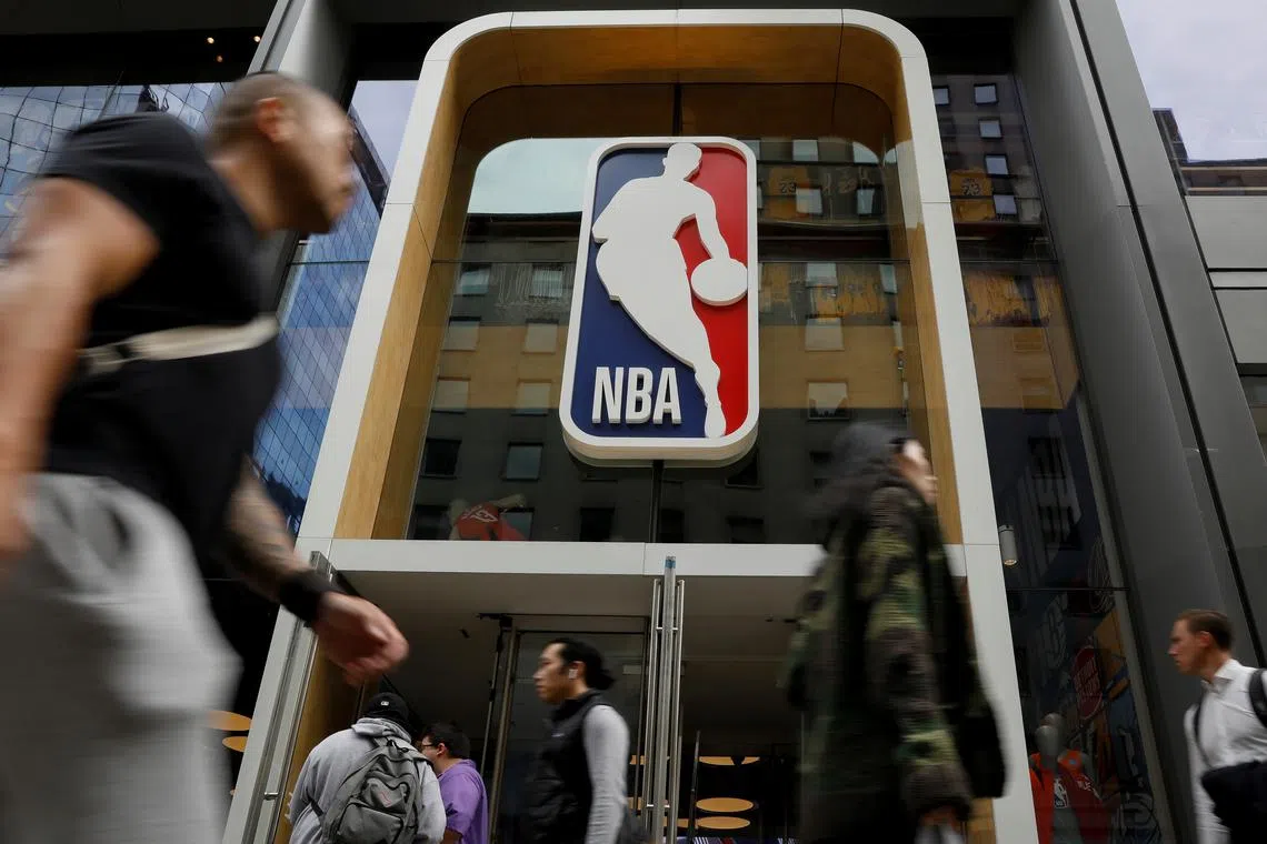 FILE PHOTO: The NBA logo is displayed as people pass by the NBA Store in New York City, U.S., October 7, 2019. REUTERS/Brendan McDermid/File Photo