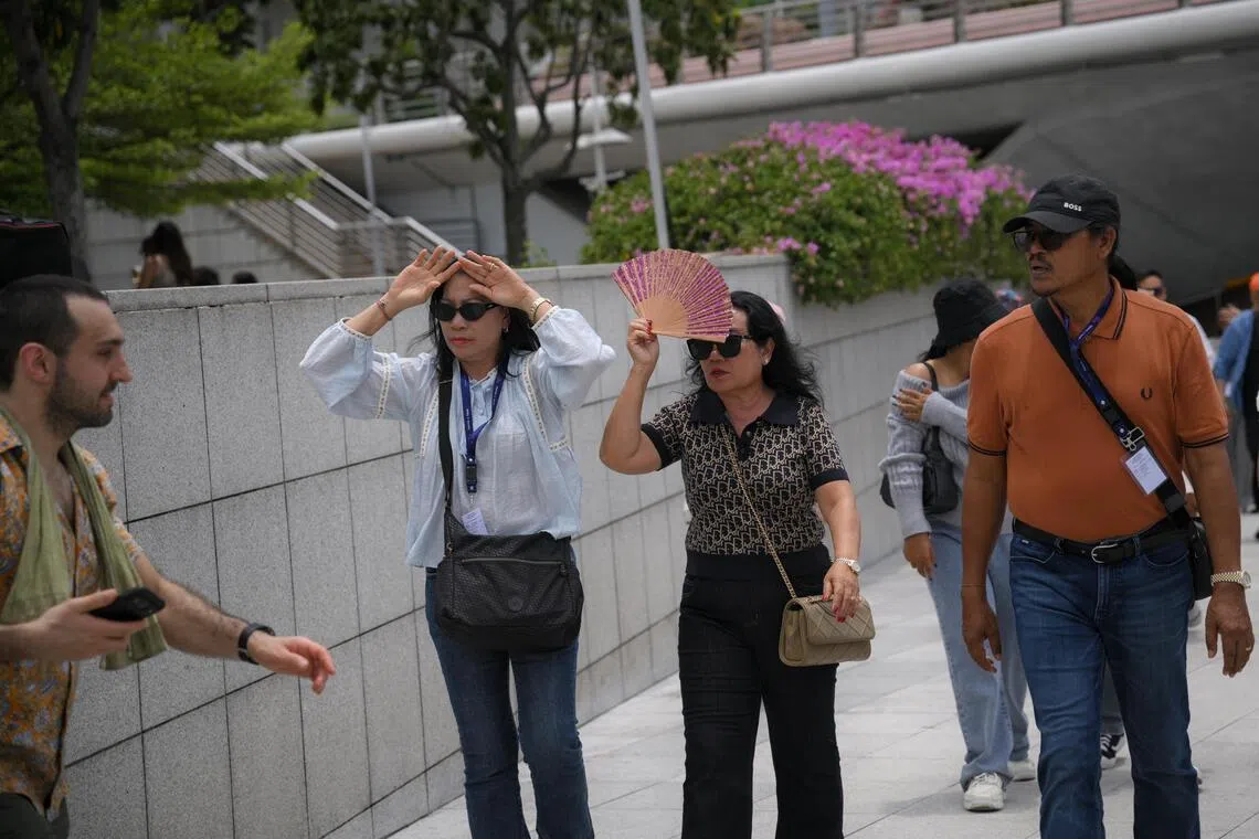 People shield themselves from the sun during a hot day at the Merlion Park on March 26.