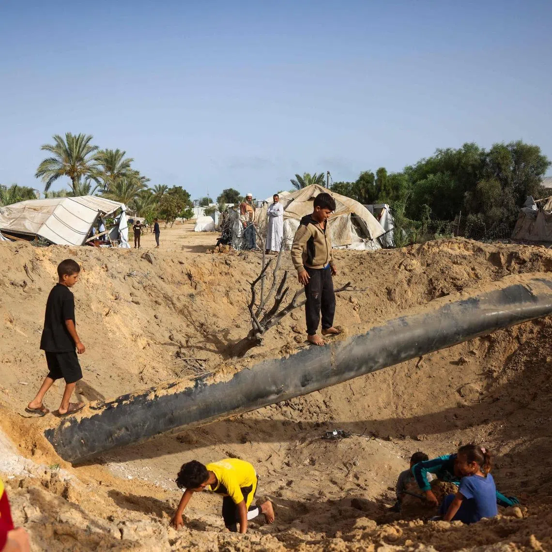 Palestinian children gather around a crater following overnight Israeli bombardment in Khan Younis, in the southern Gaza Strip, on May 19.