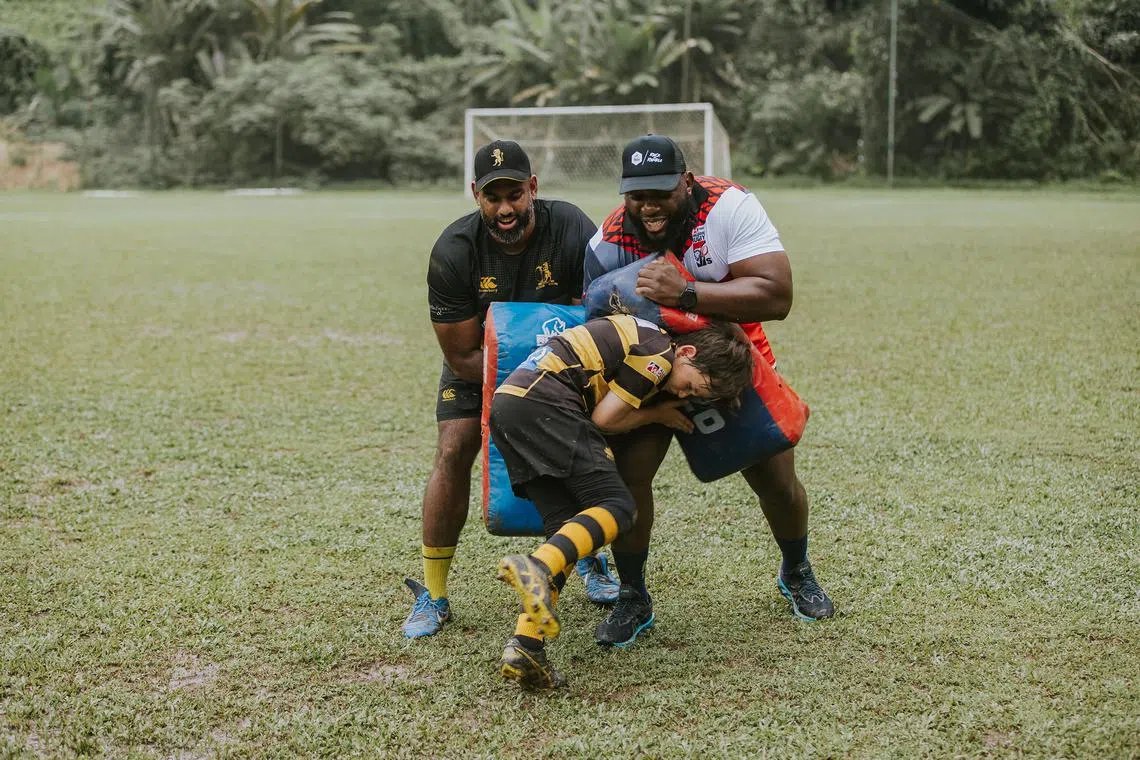 Former South Africa player Tendai Mtawarira (right) holding a rucking shield during a rugby clinic at with the SCC Dempsey Field on Thursday.