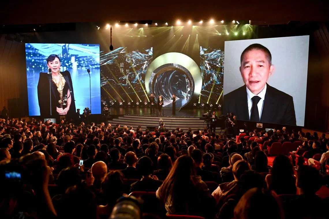 Hong Kong actor Tony Leung Chiu Wai (right) listens to his wife and actress Carina Lau (left) via video link after she picked up his Best Actor award at the 42nd Hong Kong Film Awards in Hong Kong on April 14, 2024. 