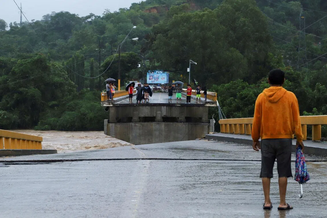 People gather at the site of a partial bridge collapse after the Cangrejal River overflowed its banks due to heavy rain brought by Tropical Storm Sara, in La Ceiba, Honduras November 15, 2024. REUTERS/Stringer