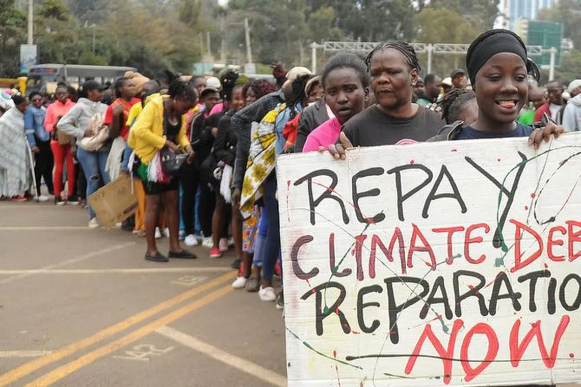 A member of the civil society holds a placard as others queue during a peaceful protest against the continent's inaugural climate summit, marching against the use of fossil fuels in the region while demanding that governments and industries transition to renewable energy in Nairobi, Kenya September 4, 2023. REUTERS/John Muchucha