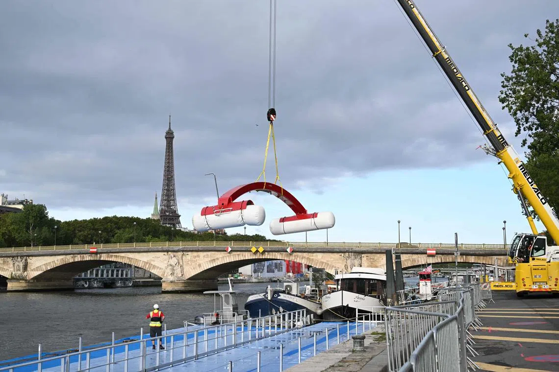 A worker dismantling a temporary venue to host a pre-Olympic swimming test competition on the river Seine after the event was cancelled due to pollution of the river in Paris on Sunday.