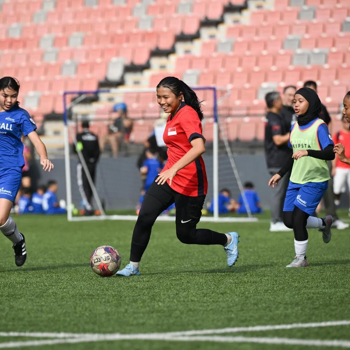 National women's footballer Irsalina Irwan (in red) playing against ActiveSG Football Academy players in an exhibition match at the AFA Football Fiesta on May 24.