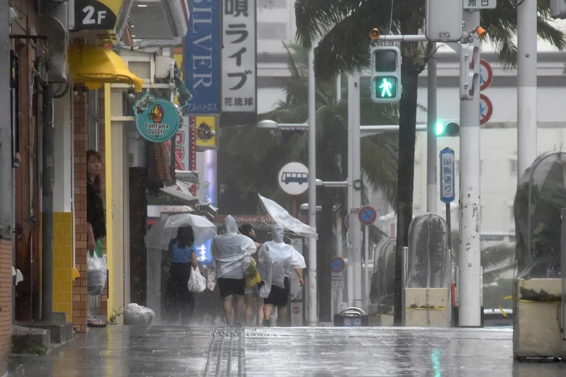 People walk along Kokusai-dori under strong wind and rain by Typhoon Khanun in Naha, Okinawa Prefecture, Japan, on Aug 2, 2023.
