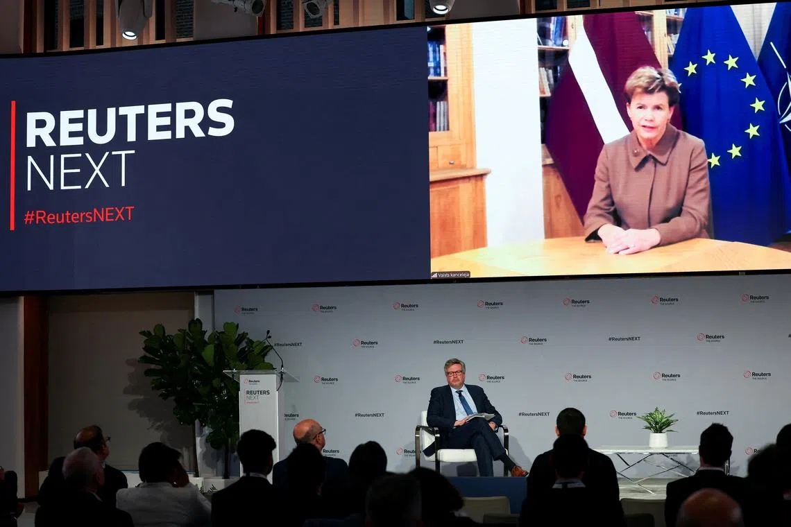 Latvia Foreign Minister Baiba Braze appears on a screen as Simon Robinson looks on, during the Reuters NEXT conference in New York City, U.S., December 10, 2024. REUTERS/Mike Segar