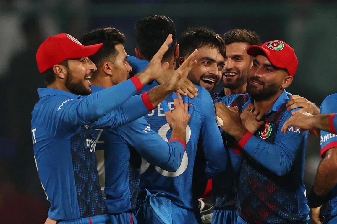 Afghanistan players celebrate their defeat of World Cup defending champions England by 69 runs, in New Delhi.