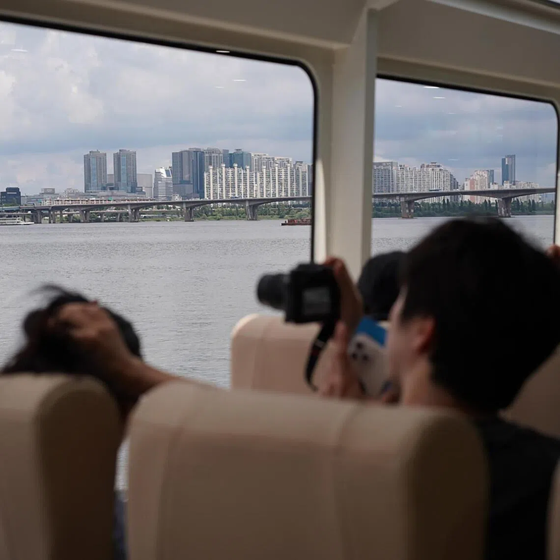 A passenger takes out a camera to take Seoul's cityscape ouside the window of Hangang Bus.