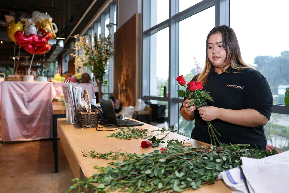 Ms Arfah Mohamad Nasir, 23, working on a flower bouquet at the Far East Flora Centre. Lower-wage resident retail workers can expect an annual salary bump from Sept 1.