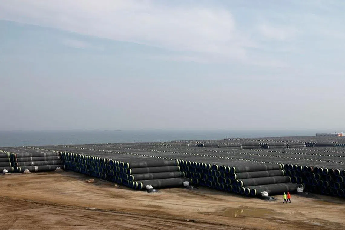 FILE PHOTO: Technicians walk beside pipes for the Nord Stream pipeline at a storage facility in Mukran on the Baltic sea island of Ruegen April 8, 2010.   REUTERS/Christian Charisius/File Photo