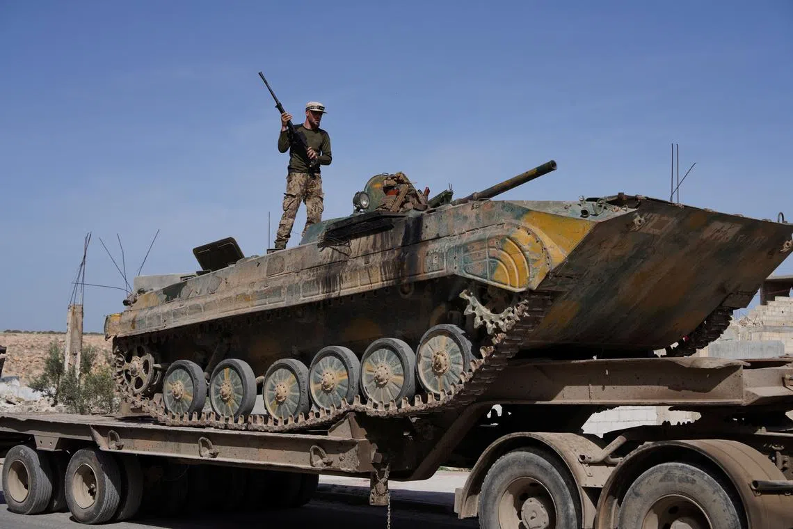 Syrian troops ride atop a towed military vehicle as they head towards the Syrian-Lebanese border following clashes with Lebanese soldiers and armed groups, in Qusayr, Syria, March 17, 2025. REUTERS/Karam al-Masri