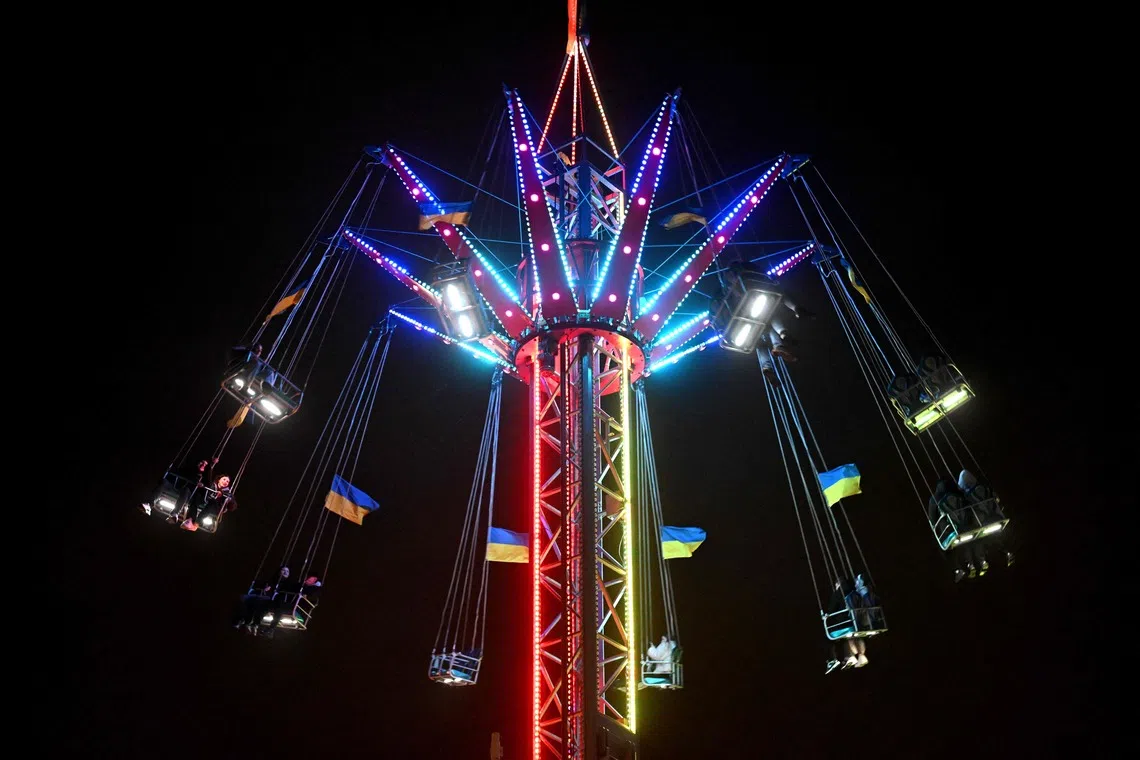 Visitors ridng a carousel at the Christmas market in Kyiv on Dec 1, 2025, amid the Russian invasion in Ukraine. (Photo by Sergei GAPON / AFP)