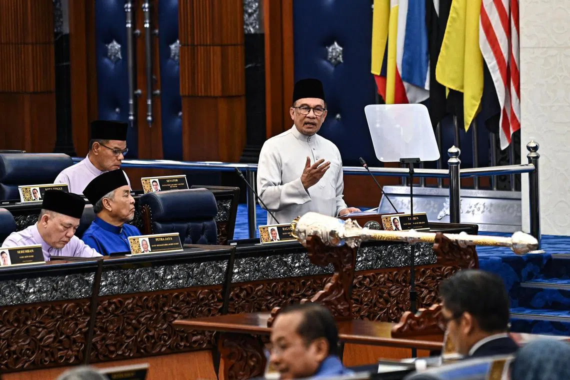 This handout photo taken and released by Malaysia's Department of Information on October 18, 2024 shows Malaysia's Prime Minister and Finance Minister Anwar Ibrahim (C) delivering his speech on the 2025 national budget at the Malaysian Parliament in Kuala Lumpur. (Photo by FAMER ROHENI / MALAYSIA'S DEPARTMENT OF INFORMATION / AFP) / - NO Marketing campaign / -----EDITORS NOTE --- RESTRICTED TO EDITORIAL USE - MANDATORY CREDIT "AFP PHOTO /  Malaysia's Department of Information" - NO MARKETING - NO ADVERTISING CAMPAIGNS - DISTRIBUTED AS A SERVICE TO CLIENTS
