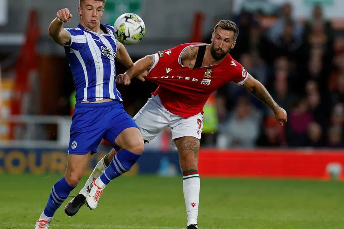 Soccer Football - Carabao Cup - First Round North - Wrexham v Wigan Athletic - Racecourse Ground, Wrexham, Wales, Britain - August 8, 2023 Wigan Athletic's Charlie Hughes in action with Wrexham's Ollie Palmer Action Images via Reuters/Jason Cairnduff/File Photo